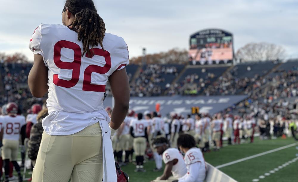A student athlete watches his teammates on the sidelines during the final moments of the 2021 Harvard-Yale game.