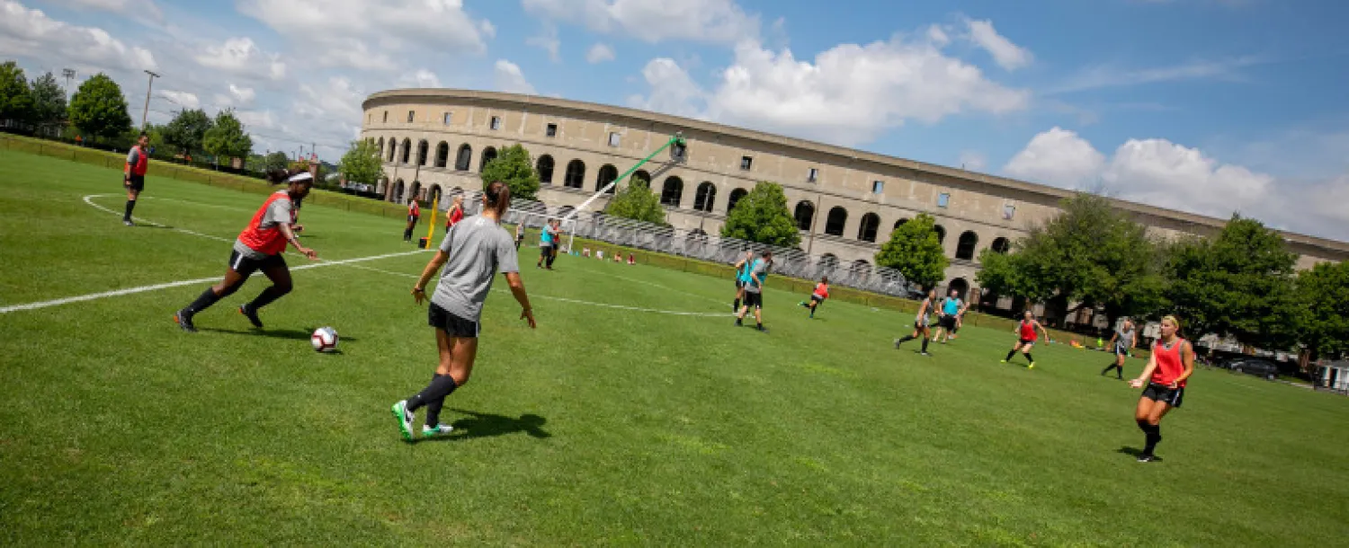 Members of the Harvard community playing soccer outside of Harvard Stadium.
