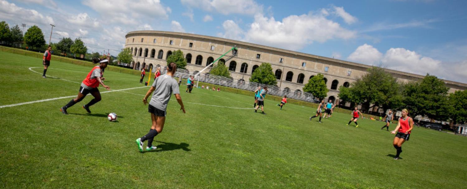 Members of the Harvard community playing soccer outside of Harvard Stadium.