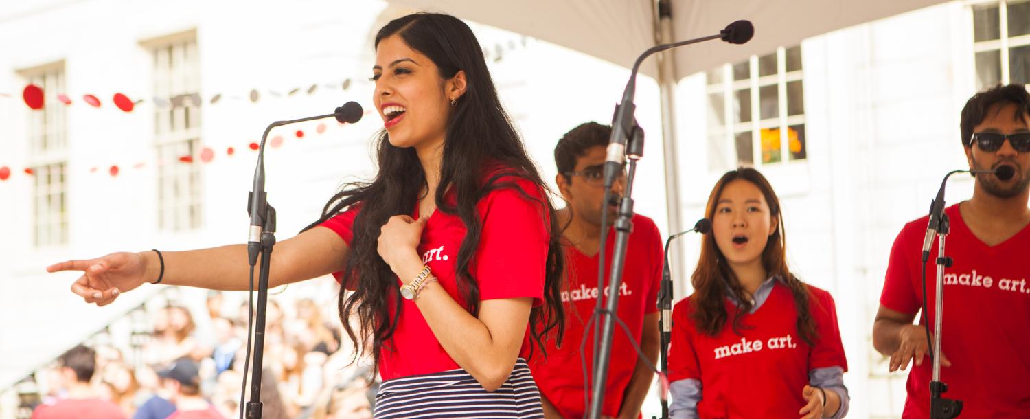 Students singing on stage, 1 soloist and 3 in the background