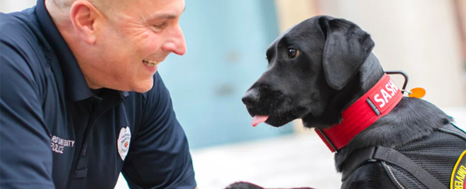 Sasha offers a paw to her handler, Officer Steven Fumicello.