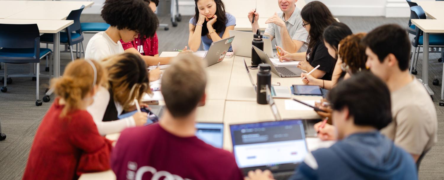 Several students sitting around a table in a classroom.