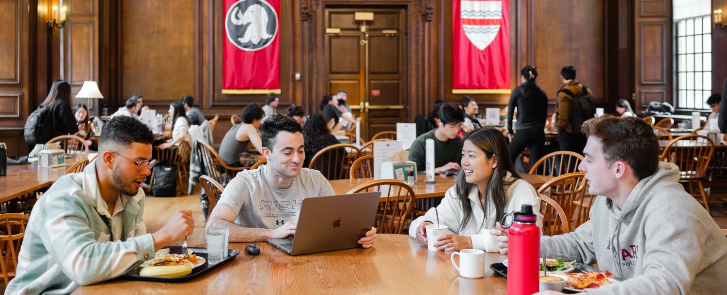 4 students sitting in Eliot Dining Hall eating lunch