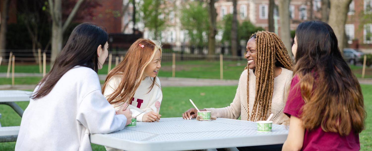 4 femal students laughing and eating ice cream at a table in JFK park