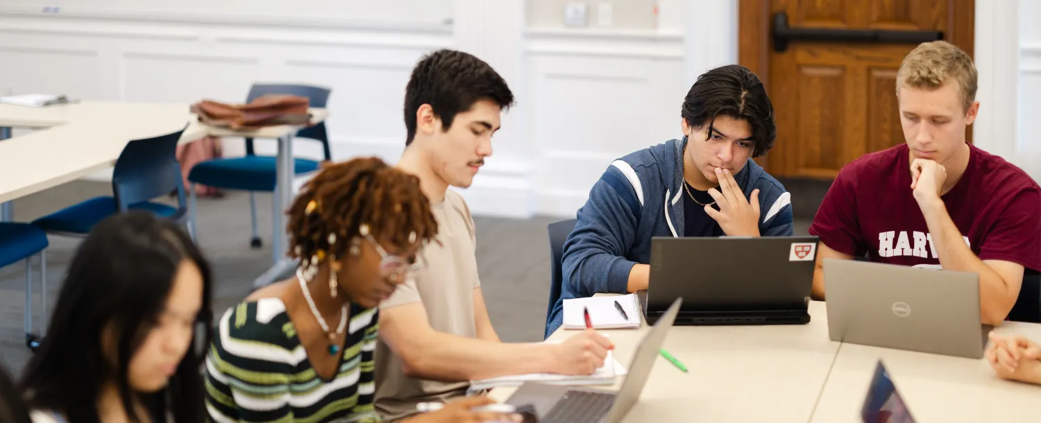 Students sit at table with laptops