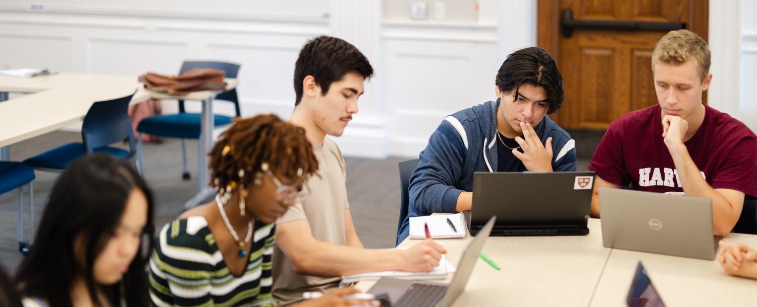 Students sit at table with laptops