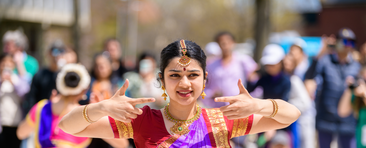 Dancer in traditional attire performing outdoors in front of a crowd.