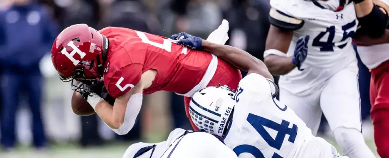 Harvard football player being tackled by a Yale player during a game.