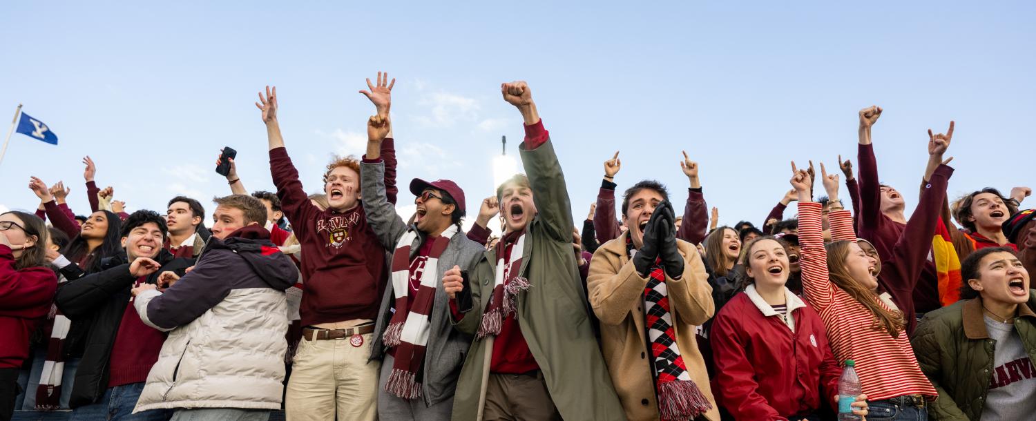 A line of Harvard College students cheer empatically in the front row at the Harvard-Yale game.