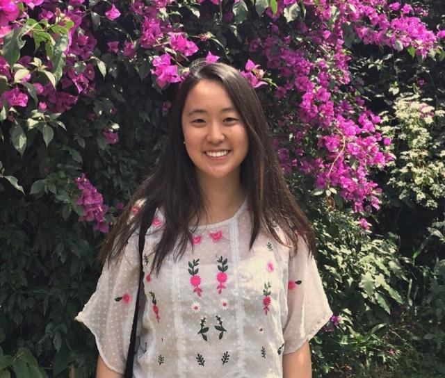 Student standing in front of flowers.