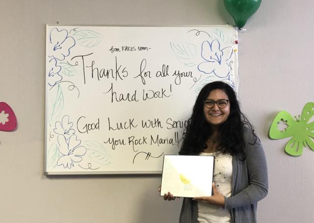 Maria posing in front of a farewell message at the end of her internship. 