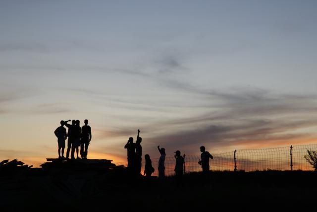 Silhouette of a group of people against a sunset background