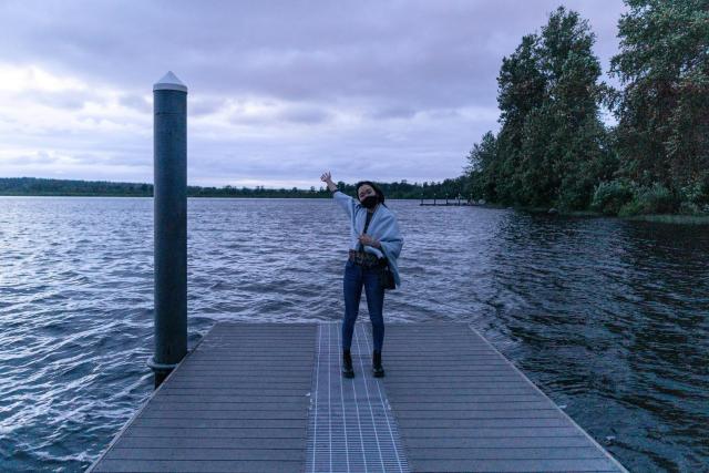 I am posing happily by a lake in my hometown near Seattle, WA. It's really cloudy and getting dark. 