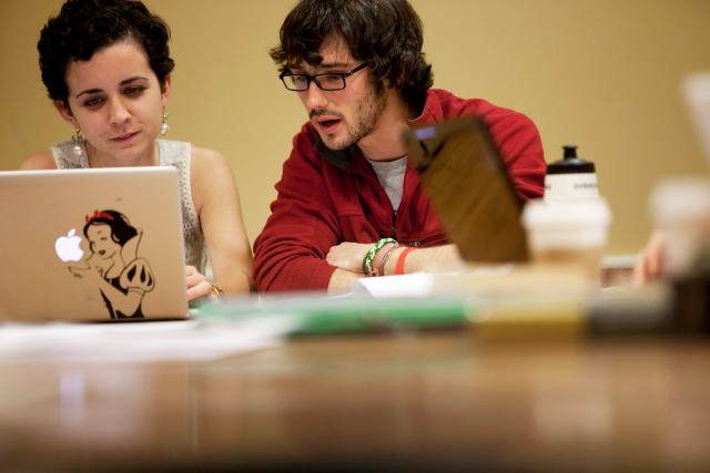 Two students sharing a laptop and speaking to one another