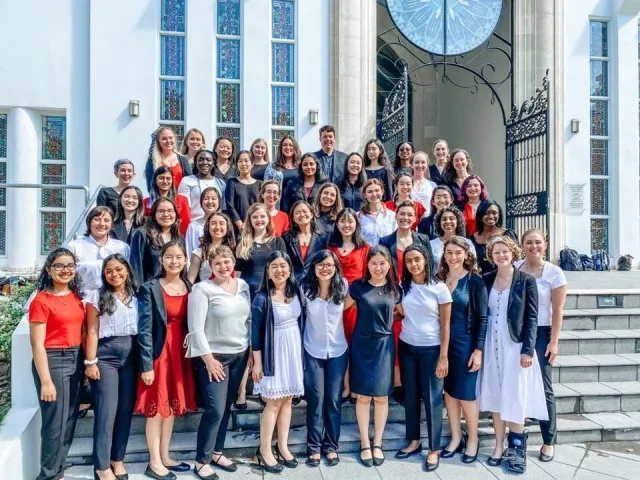 Members of the Radcliffe Choral Society standing on the steps of a church, in formal concert wear.