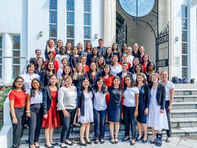 Members of the Radcliffe Choral Society standing on the steps of a church, in formal concert wear.