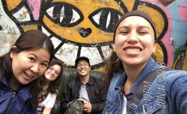 4 students in front of wall art in Paris.