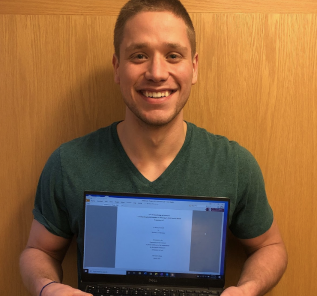 Student Holding a laptop in front of him