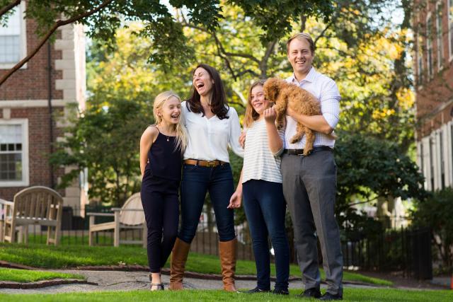 A portrait of Janine Santimauro and David Deming, faculty deans of Kirkland House, with their two daughters and dog.