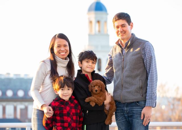 A portrait of Leslie Duhaylongsod and Eric Beerbohm, faculty deans of Quincy House, with their two sons and dog.