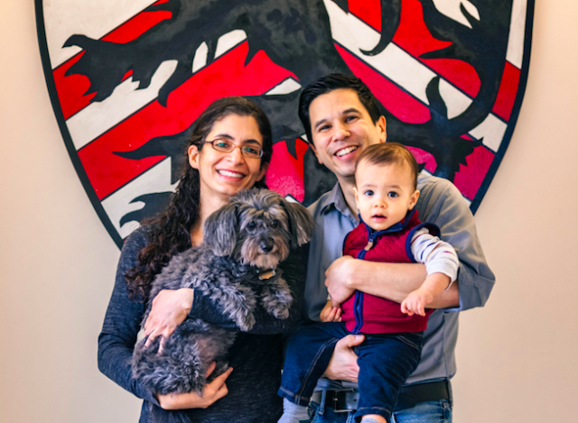 A portrait of Kiran Gajwani and Stephen Chong, faculty deans of Winthrop House, with their son and dog.