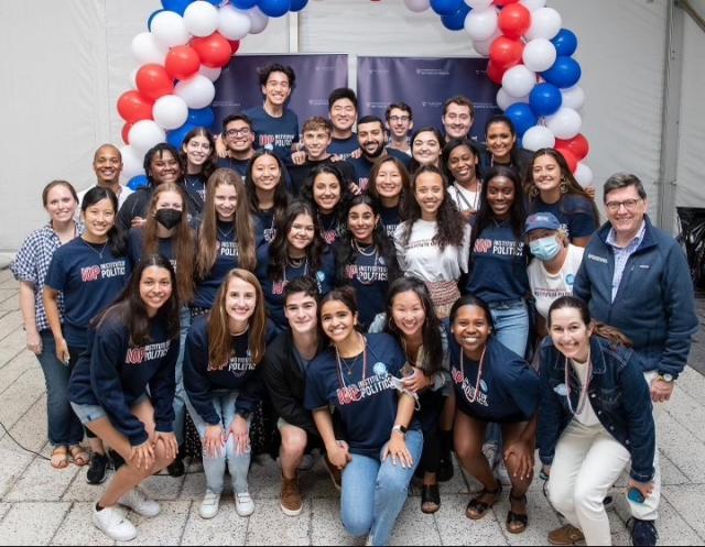 group of students in matching IOP t-shirts in front of red, white, and blue balloons