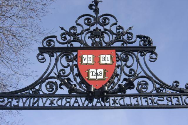 A harvard logo pinned to the top of a gate wall
