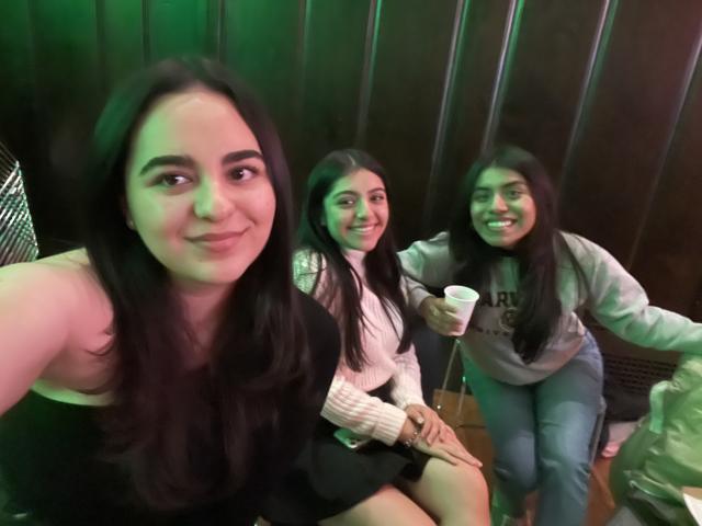 Three students are seated to take a picture. They are at a social event. 