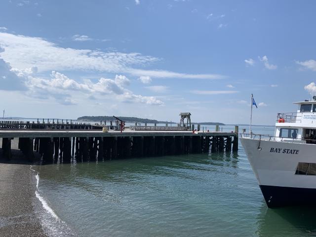 Picture of pier stretching out into the ocean with a white boat coming in.