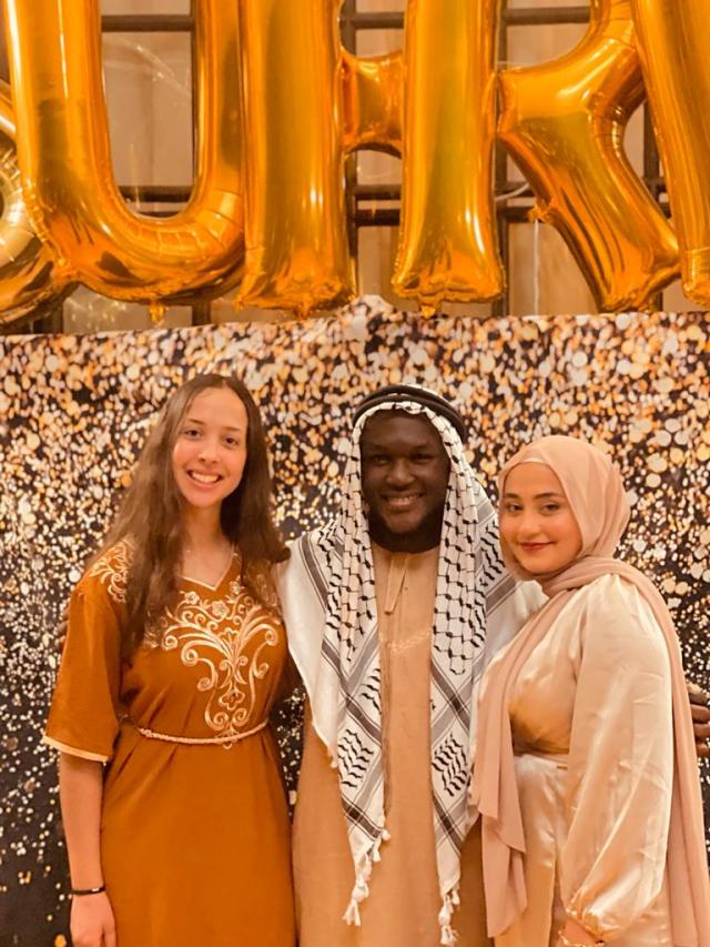 A group of friends and I wearing traditional clothing and posing in front of large balloons that spell out Sufra!