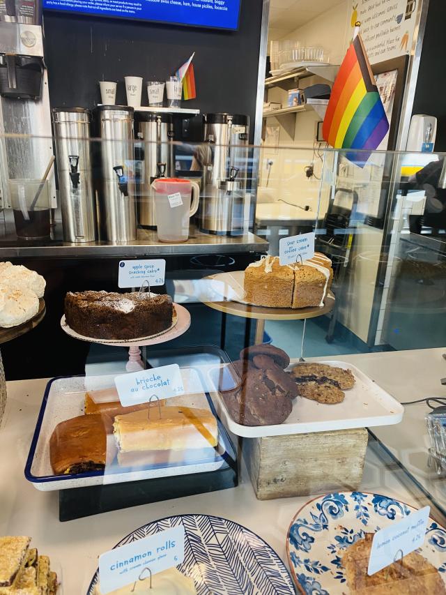 The bakery case of flour bakery + cafe filled with pastries, with a rainbow pride flag in the background. 