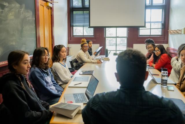 students and professors sitting around a table having a discussion