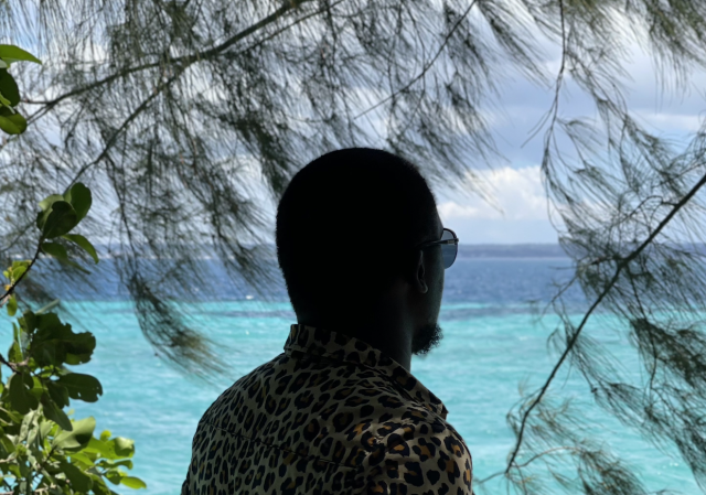 A photo of a man in sunglasses looking at blue ocean waters.