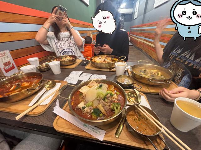 Five individual hot pot soups are pictured at a table.