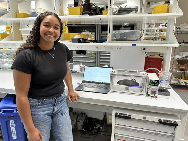 Senior Tiahna Padilla in the lab standing next to her thesis project.