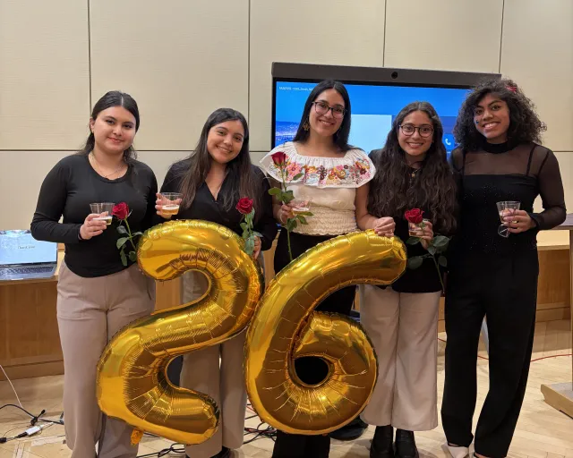 Lizbeth and four friends who just presented at the Latinx Senior Thesis Forum pose for a photo. Each person is holding a red rose.