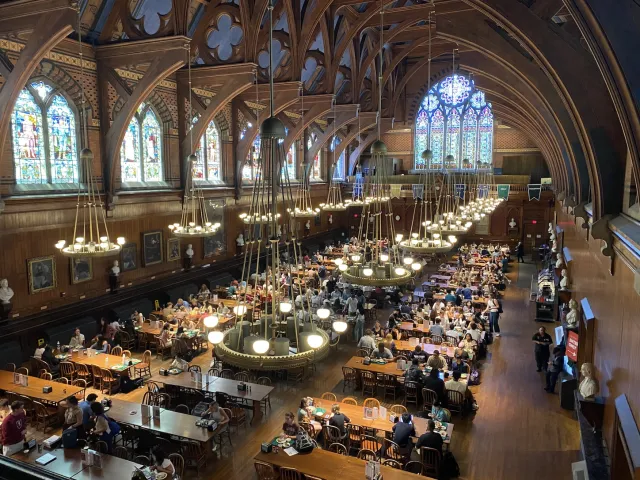 Indoor dining hall with rows of dining tables and stained glass windows