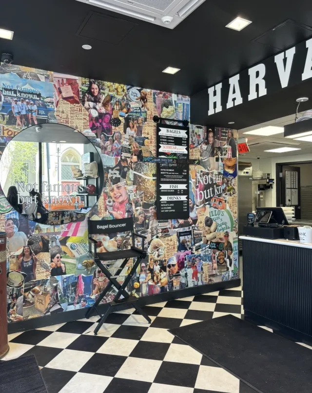 Inside of a bagel shop with a collage of picture, a mirror, and checkered floor tiles