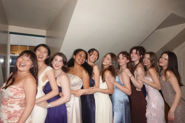 Group of ten girls in formal dresses, lined up and laughing 