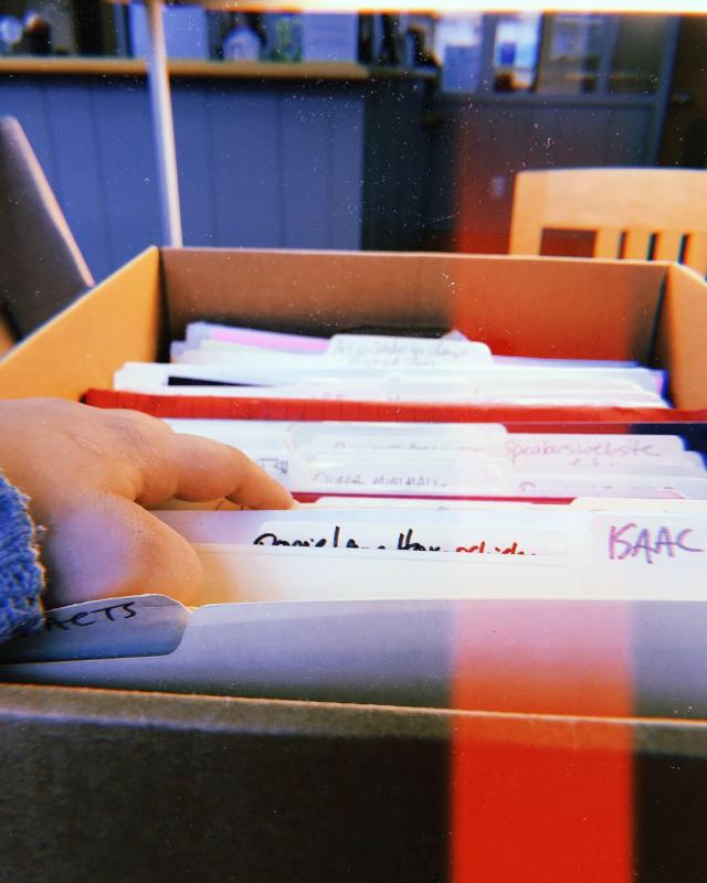 Hand going through files in a box at an archive 