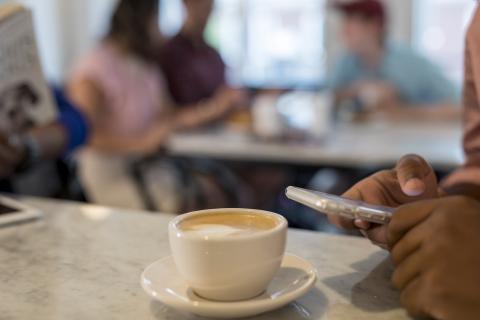 Student using phone at a coffee shop