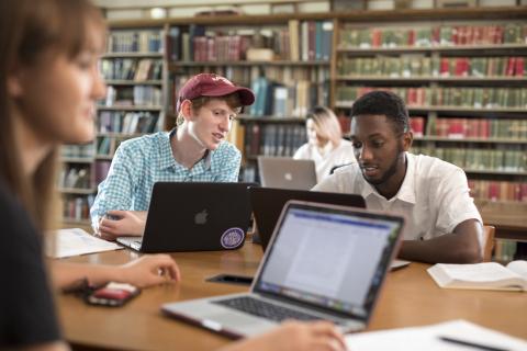 Two students looking at a laptop in a library study room