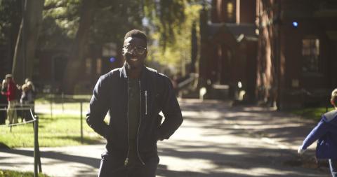Student smiling and walking through Harvard Yard