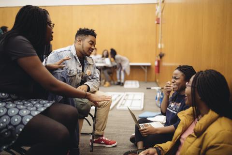 A group of students exchange smiles during a break in choral practice