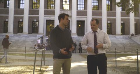 A student and professor Dustin Tingley walk and talk through Harvard Yard.