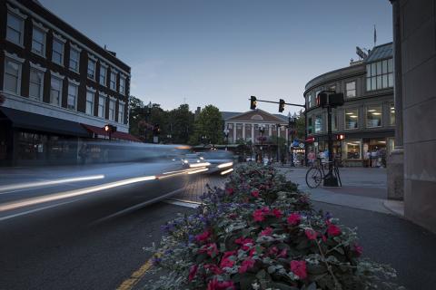 Harvard Square in the evening with cars driving by.