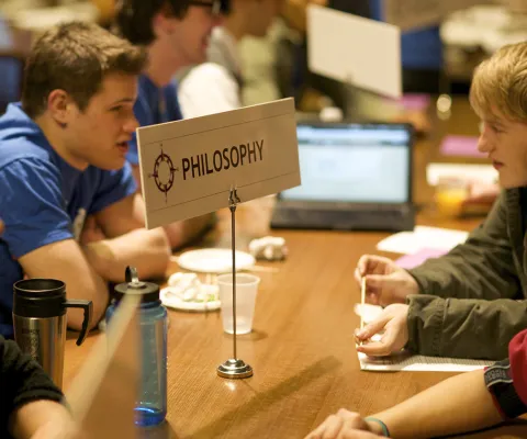 student sitting at a table with a Philosophy advisor at the fair