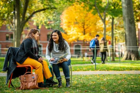 Two Students Sitting in Harvard Yard in the Fall