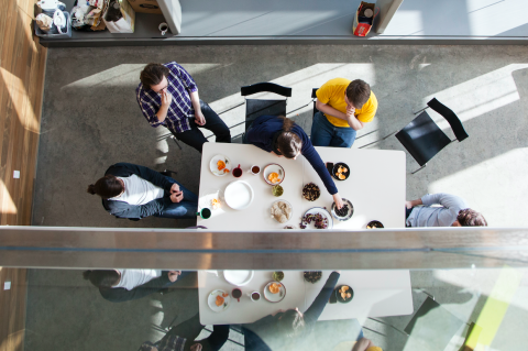 A group of people eat a meal together while in a meeting.