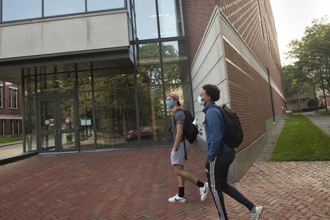 2 students walking on campus wearing masks